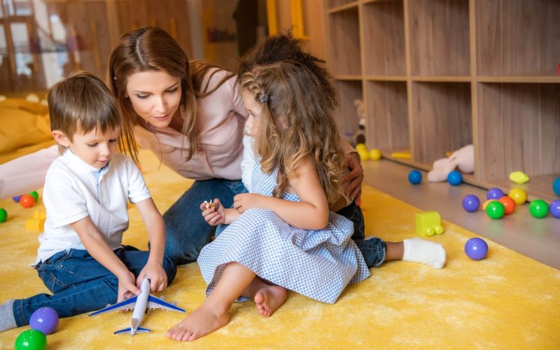 tutor-hugging-adorable-kids-on-carpet-in-kindergarten-1.jpg